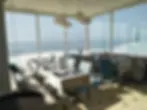empty-chairs-tables-by-sea-against-window.webp