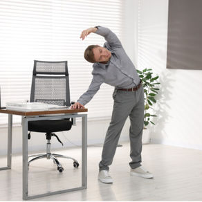 Person doing a simple standing stretch at a desk, showing how short exercise snacks can fit into a workday.
