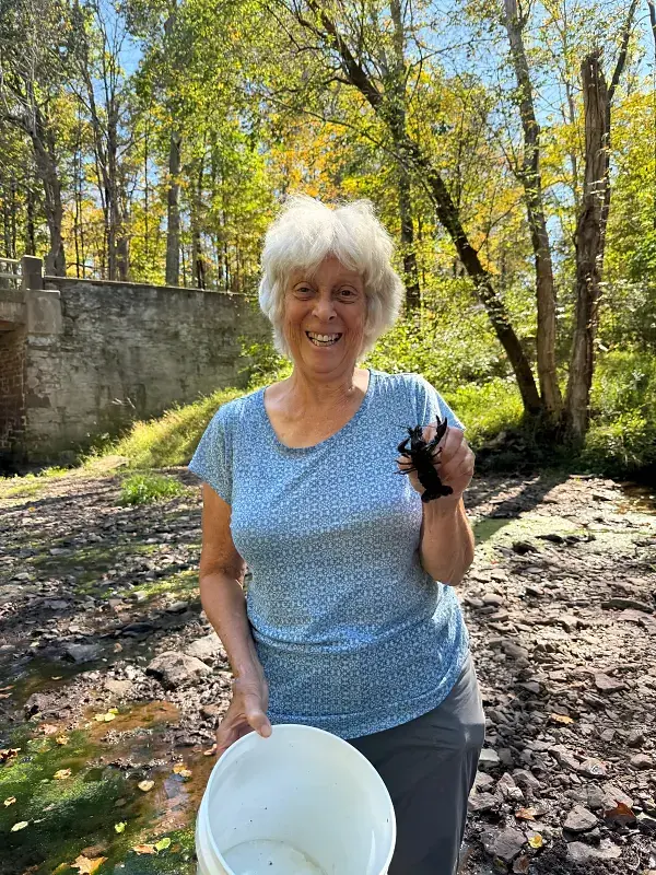 Smiling woman with a crayfish and bucket for community stewardship