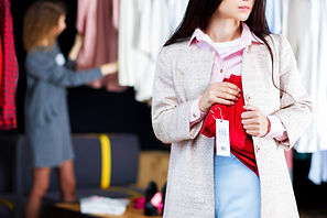 Closeup of young woman is stealing red jeans in store, shop, boutique at shopping center. 