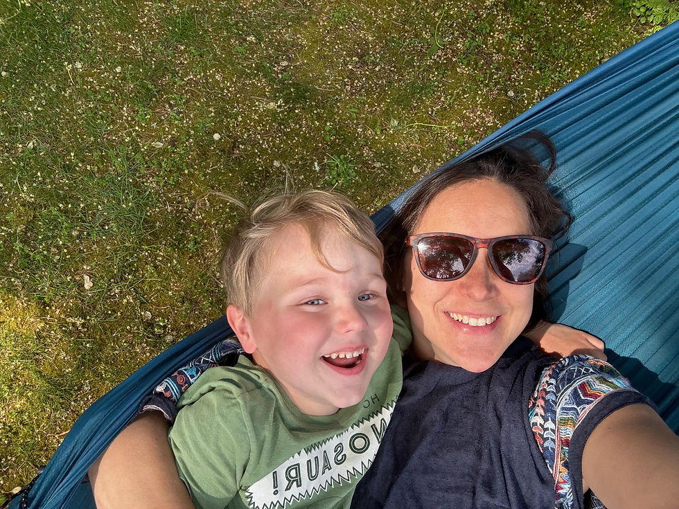 A woman, Teryn, lying in a hammock with a little boy. They are smiling and laughing together.