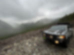 A 4x4 truck parked on the edge of a mountain overlooking a lush valley