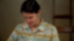 Sam, a transmasculine teenager played by American actress Linsey Godfrey, in the show Cold Case. He is sitting in a school classroom, looking down with a distressed expression, starting to cry. He is light-skinned with short, dark brown hair, wearing a green-and-yellow flannel shirt.