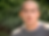 Ryan, a trans man in the documentary Changing Sexes. He is sitting outdoors, with a green tree visible in the blurred background. He has light brown skin, black hair cut in a buzzcut, and dark brown eyes. He is wearing a grey t-shirt.