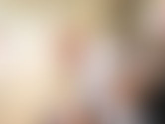 Bishop in gold vestments and mitre smiles and greets a young child held by his mother during a church liturgy, with clergy and parishioners in the background.