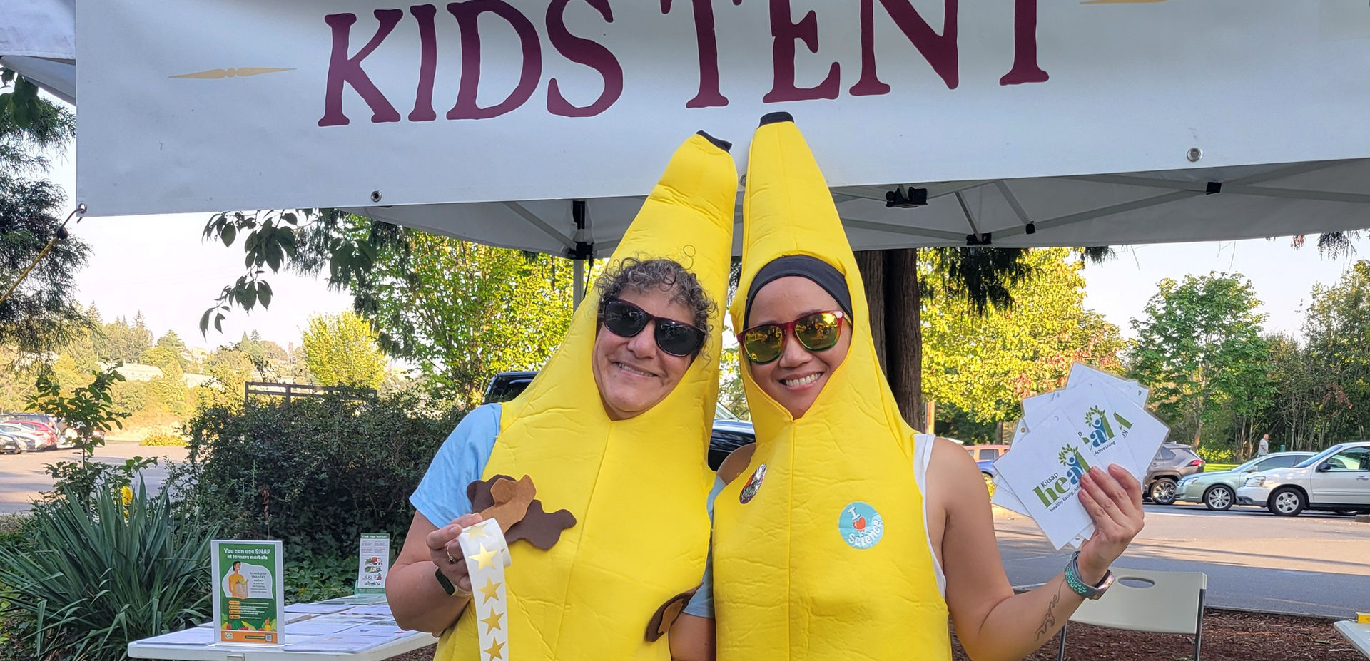 Two KPHD employees dressed as bananas at a farmers market