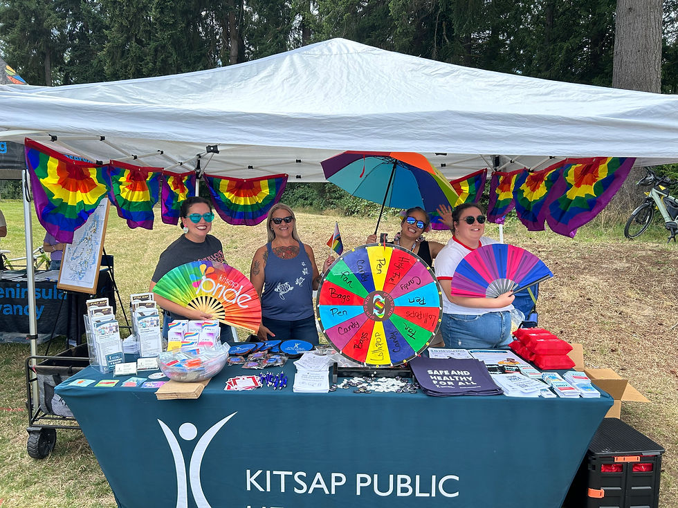 A group of Health District employees at a booth decorated with rainbow bunting.