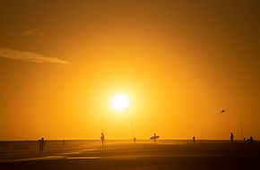 Personas en una playa al atardecer.