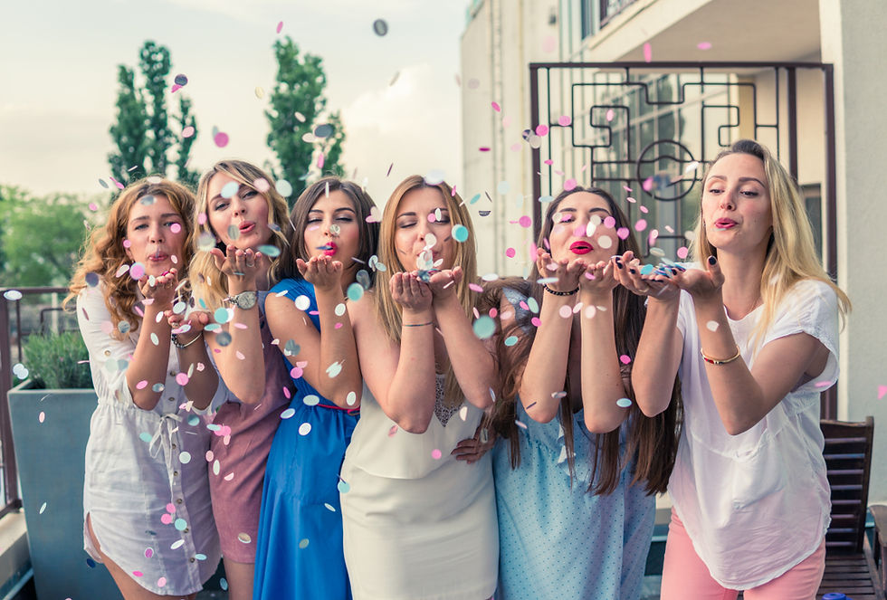 Five women at a French bridal shower blow bubbles in the air, enjoying games and challenges with lighthearted fun.