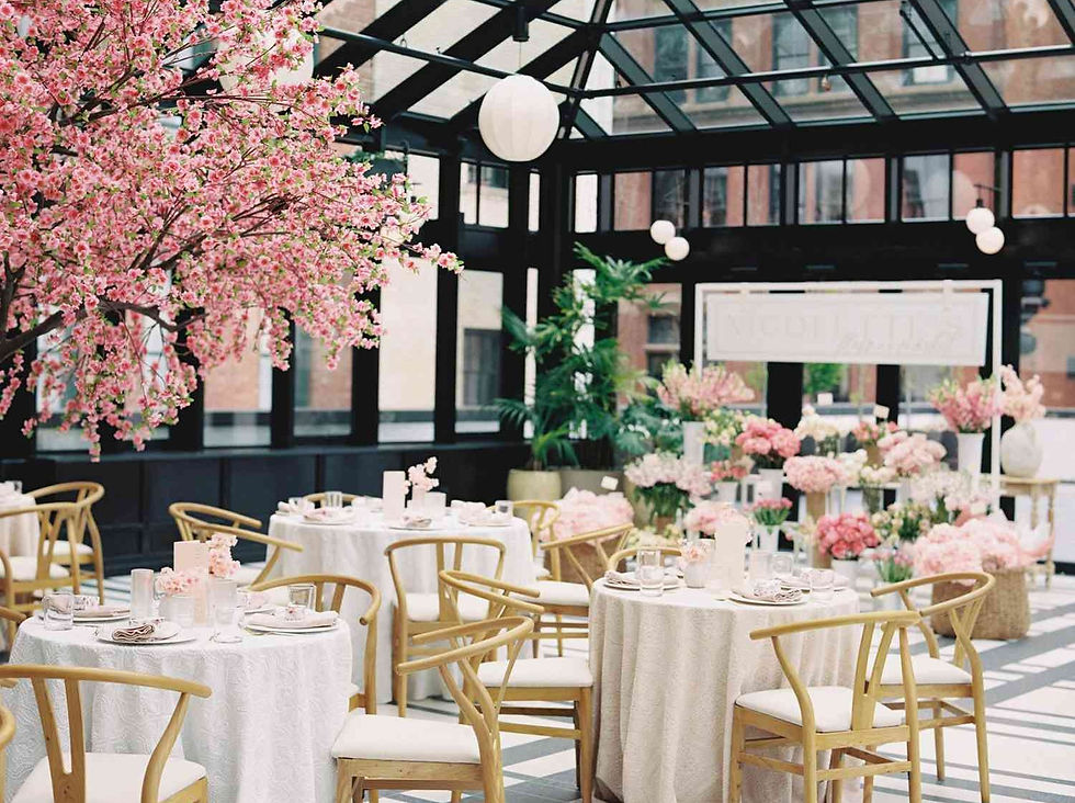 A wedding reception in a glass building adorned with pink flowers, capturing the charms of a French bridal shower.