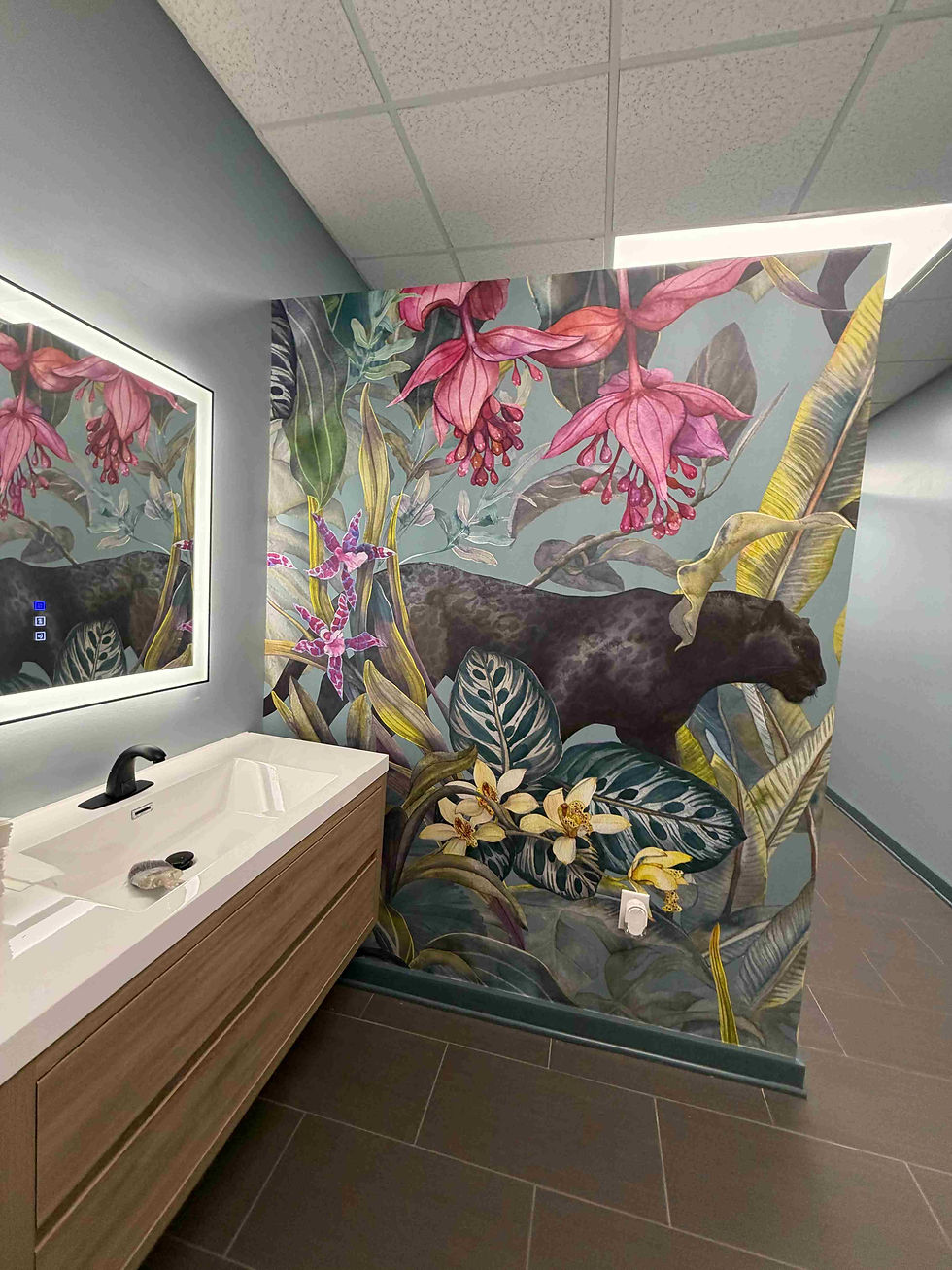 Bathroom with floral and panther mural, wooden sink cabinet, and illuminated mirror. Soft gray walls create a calm ambiance.
