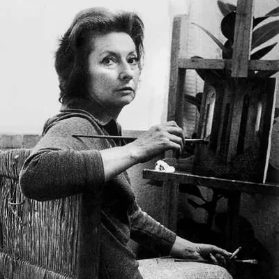 black and white portrait of remedios varo in her studio at her easel as she looks behind her