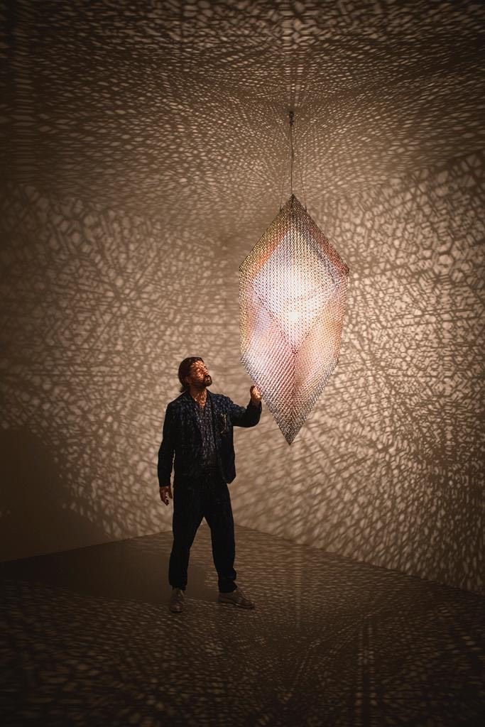 Conrad Shawcross standing next to his artwork 'Slow Arc Inside a Cube XI' (2020) in Noor Riyadh 2023