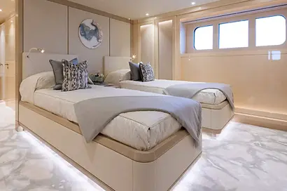 example of insurance & tax services by artelier featuring a double twin bedroom inside a superyacht with a marble like flooring and circular abstract wallpieces in creams and golds and whites