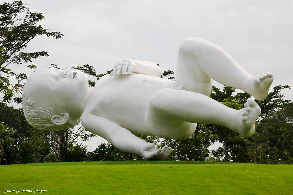 64. © Photo by Black Diamond Images showing a huge contemporary art installation of a white naked child alseep as it floats above an outdoor garden park space
