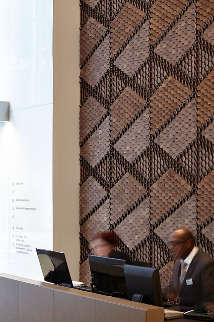 Aldermary House reception area featuring two receptionist moving in a blurred motion based in london with a large feature wall made of geometric hive shapes in wood by giles miller studio.jpg