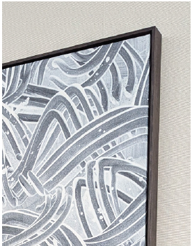 A close-up depicts a framed abstract painting, positioned at a slight angle to the viewer, highlighting its texture and details. The artwork features a monochromatic color scheme, primarily in shades of gray and white, with thick, looping lines dominating the composition. These lines vary in thickness and intensity, creating a sense of movement and depth across the canvas. The brushstrokes are visible, suggesting a textured surface. The painting is framed in a dark, possibly wooden frame that provides a clean, contrasting border to the artwork. The background is a neutral wall, which allows the painting to stand out as the focal point. The lighting is soft and even, which minimizes harsh shadows and allows for detail visibility.
