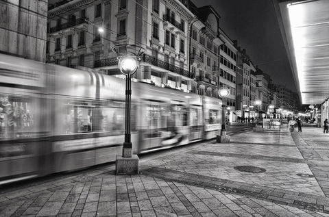 An outdoor image of the streets of geneva, switzerland with a blurred tram crossing the centre of the photograph