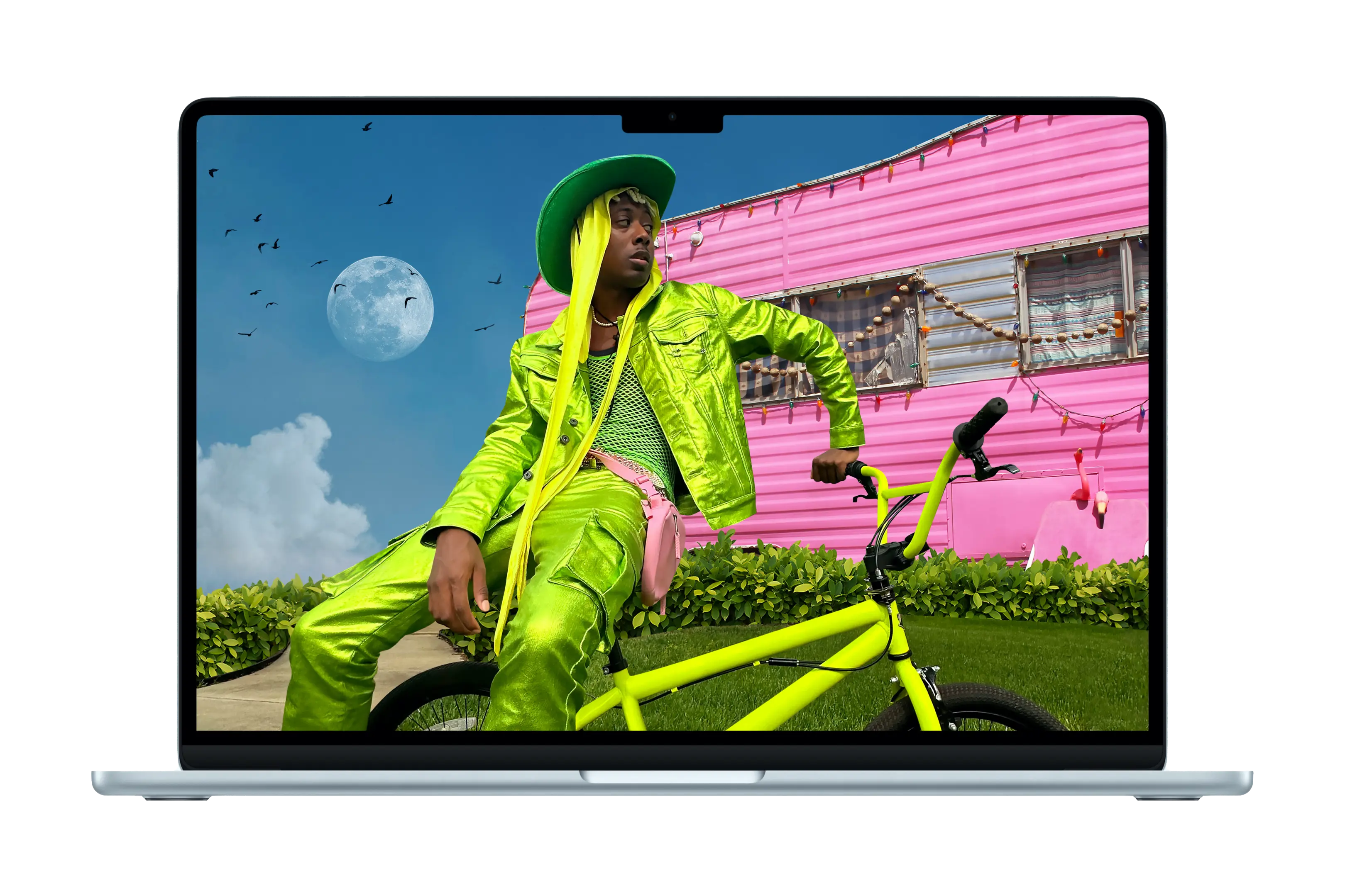 Un MacBook Air affichant une photo stylisée d’une personne habillée en vert fluo, assise sur un vélo assorti, devant un camping-car rose fluo. 