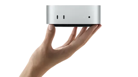 Une main tient le Mac mini M4.