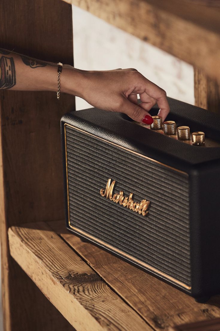 une femme qui règle le son d'une enceinte Marshall