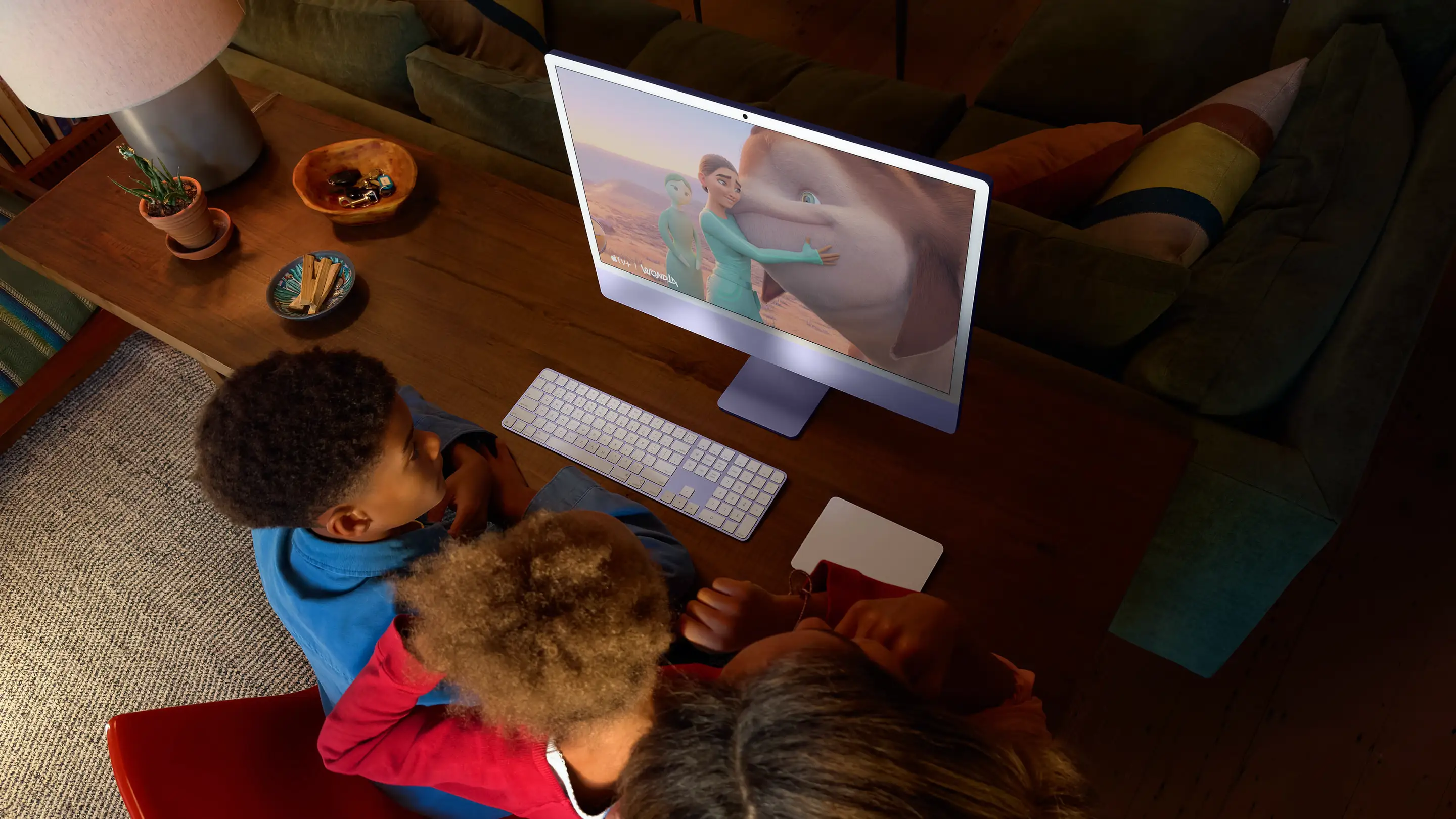 Trois personnes regardent une scène extraite d’un film d’animation sur iMac.