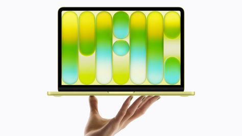 Une main tient le tout nouveau MacBook Neo en jaune agrume.