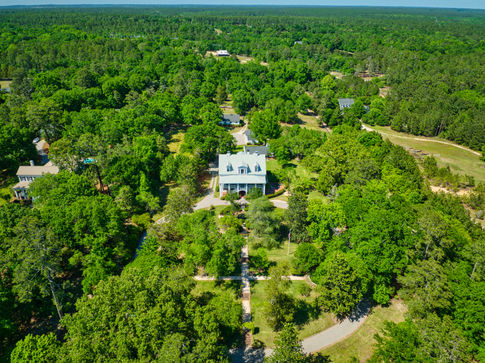 Aerial drone photograph of a large home on a wooded lot.