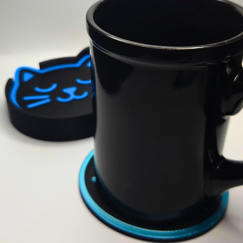 Black mug on a blue and black coaster with a cat face design. Background is white, creating a minimal and sleek appearance.