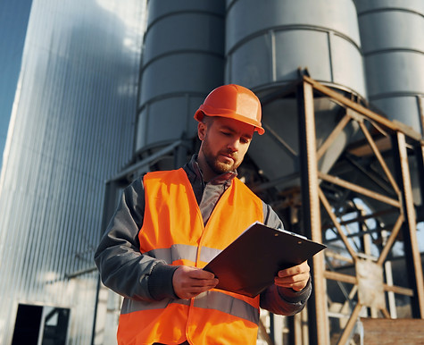 sosteniendo-el-bloc-de-notas-en-las-manos-el-trabajador-de-la-construccion-en-uniforme-est