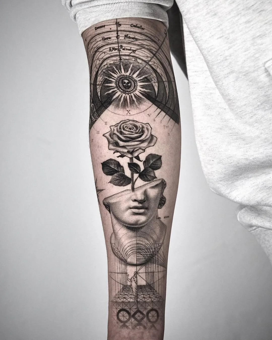 lack and grey fineline collage forearm tattoo featuring a celestial diagram, a realistic rose, a classical Greek bust, and geometric perspective architecture. Seoul Ink Tattoo, Gangnam, Seoul, South Korea.