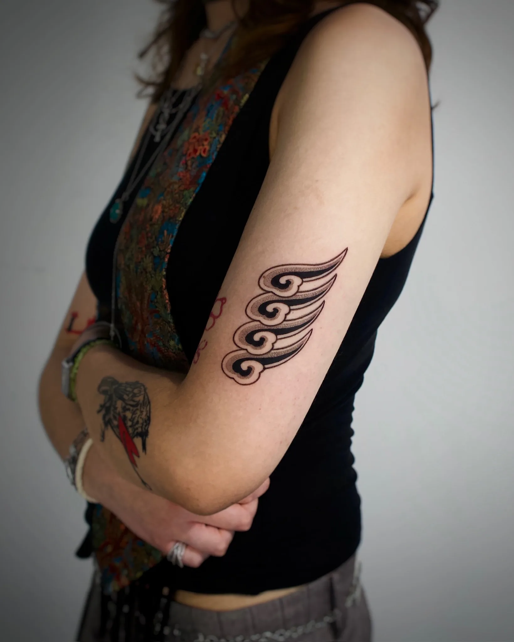 Blackwork Korean cloud wing tattoo on the outer forearm — a stylized wing shape made of layered traditional cloud forms with bold black outlines. By Vezofit at Seoul Ink Tattoo, Gangnam, Seoul, South Korea