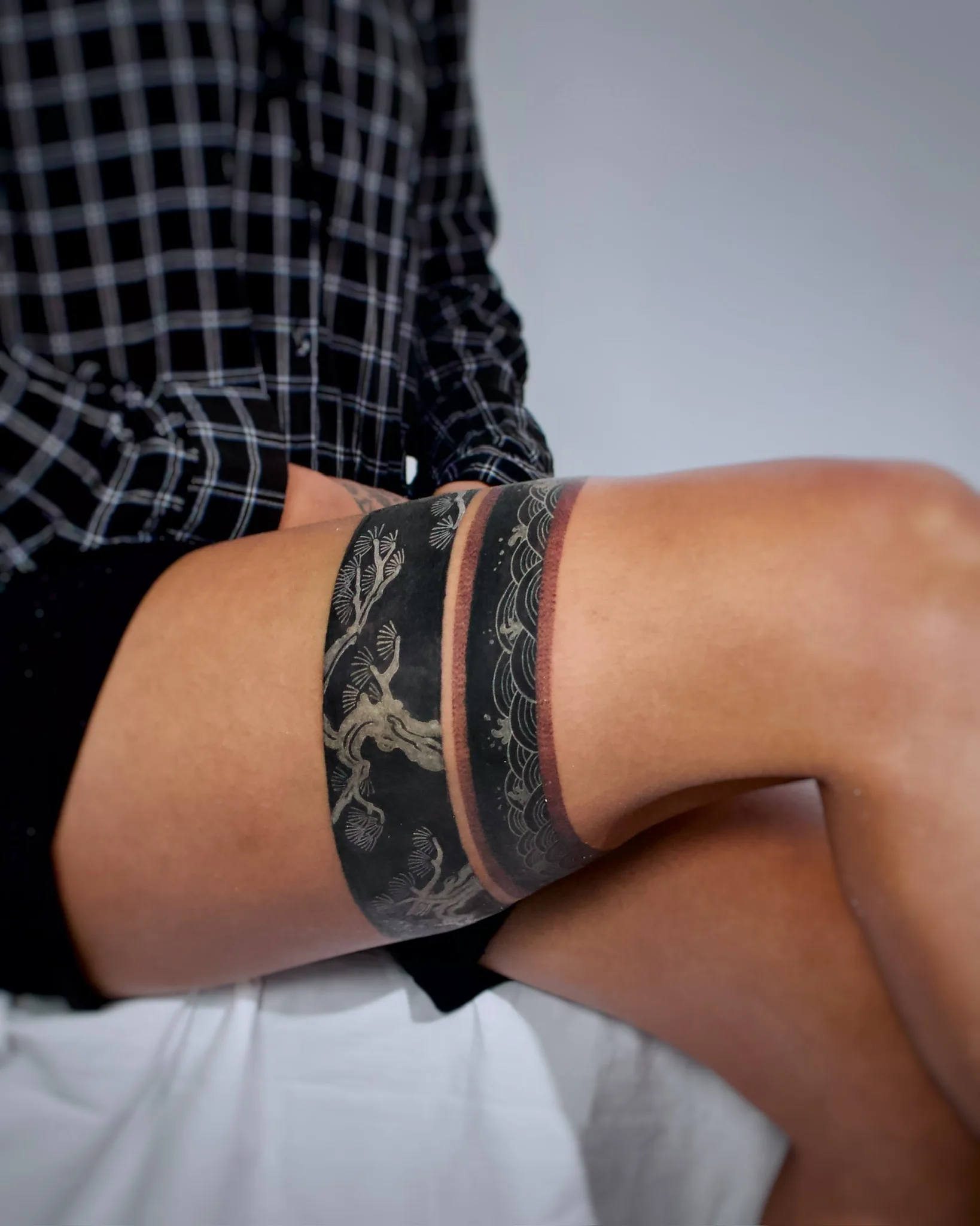 Wide blackwork Korean thigh band tattoo featuring a pine tree landscape on one side and traditional wave patterns on the other, separated by a red accent stripe. By Vezofit at Seoul Ink Tattoo, Gangnam, Seoul, South Korea