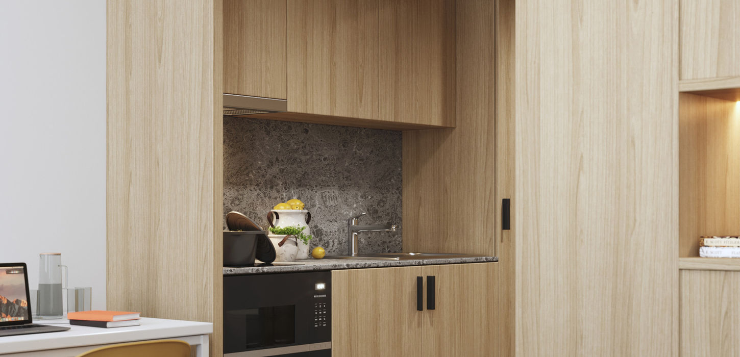 Studio avec cuisine équipée, espaces de rangement et coin repas, offrant un design compact et fonctionnel idéal pour les étudiants ou jeunes professionnels.