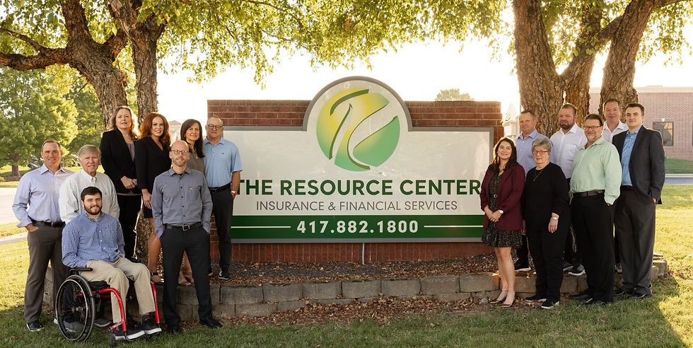 A group of people smiling near a sign for "The Resource Center" under a large tree. The mood is professional yet relaxed.