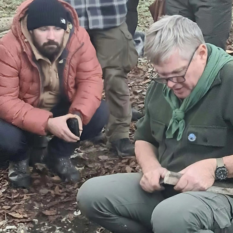 Two people whittling wood with knives at a South West Survival woodland session