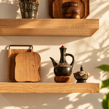 Oak shelf with cutting boards and a black ceramic coffee pot in late sun