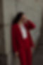 Woman in Red suit looking off into the distance in a sad manner