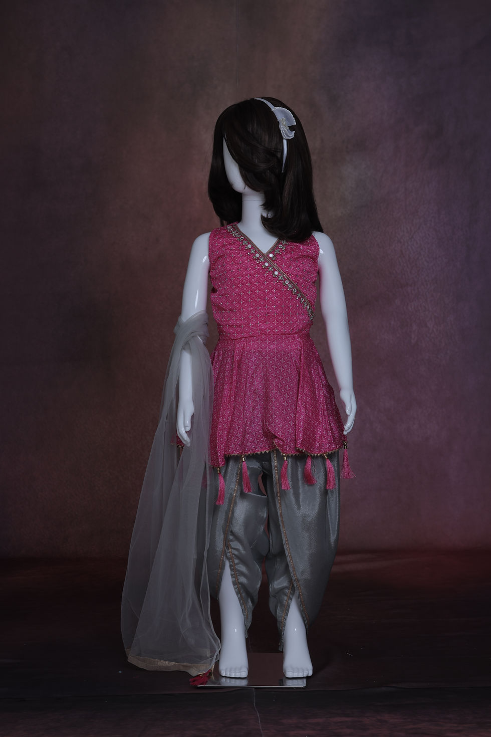 Girls' three-piece Fuchsia and Slate Grey dhoti set with a mirrorwork peplum top, draped metallic trousers, and net dupatta.
