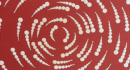Indigenous dot painting of white dots on red background in a spiral pattern.