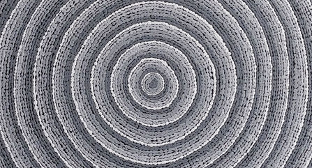 Indigenous dot painting of grey and white dots in a spiral.