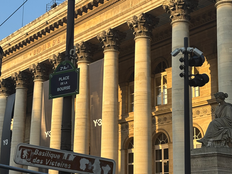 Sunlit neoclassical Bourse building in Paris with tall columns, street signs for Place de la Bourse, and clear blue sky.