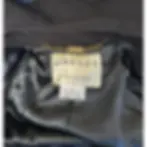 Label inside a black coat reads "JAEGER, Made in Great Britain" with fabric details. A gold chain is attached above the label.