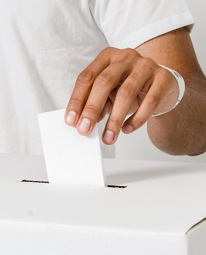 A voter placing a ballot in a voting box.