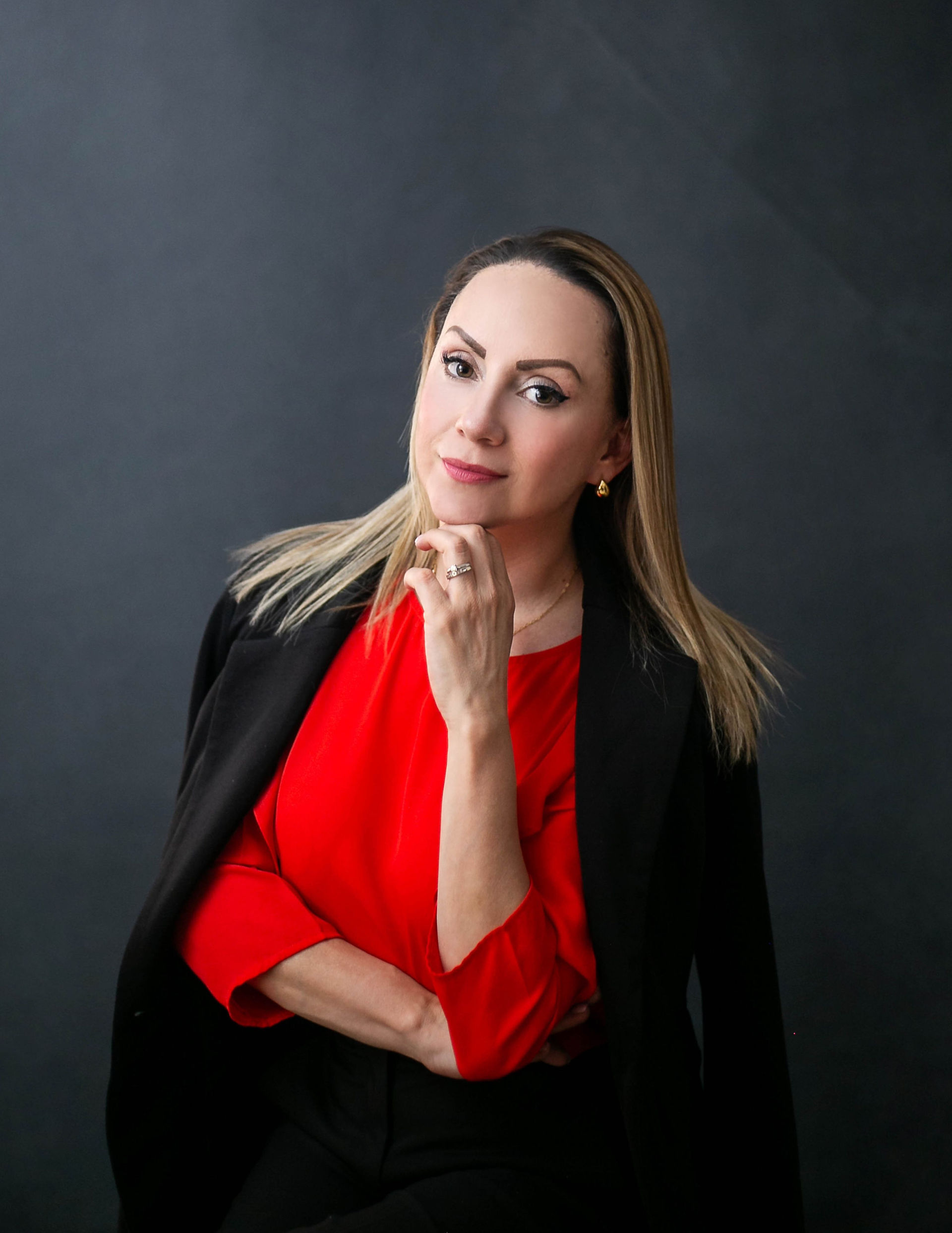 Sesión fotográfica de Retrato corporativo de una mujer rubia con blusa roja y saco negro.