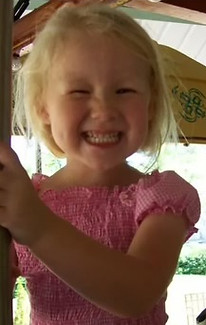 Smiling child holding a pole on a carousel ride.