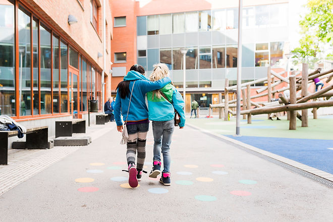 To jenter går på et skoleområde med armene rundt hveradnre