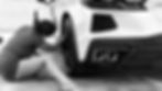 Black and white photo of a 2022 Corvette. Female detailers cleaning car wheels.