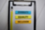 Clipboard with text "Diversity," "Equality," "Inclusion."