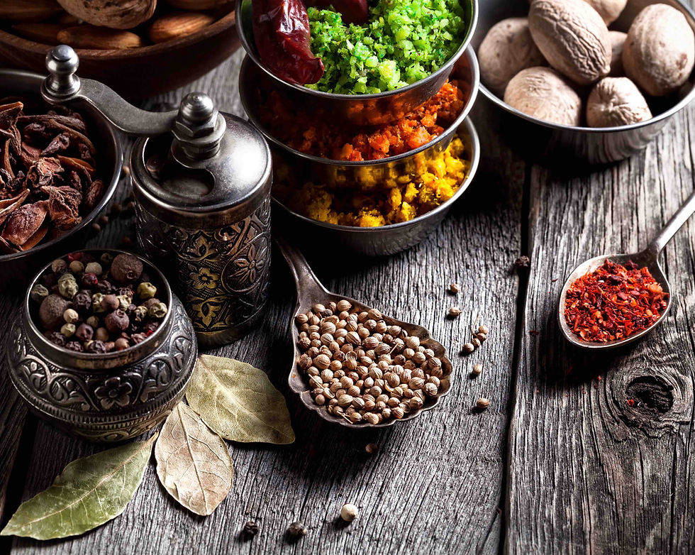 Verschiedene Gewürze in Schalen und Löffeln auf einem rustikalen Holztisch.